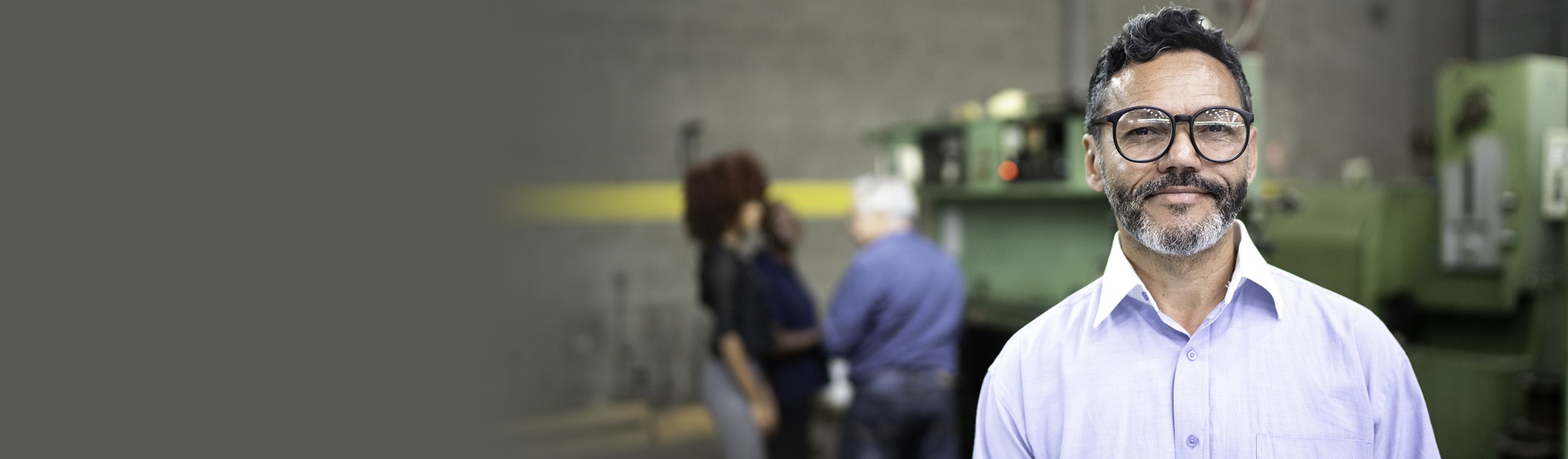 Chef de projet en chemise blanche et lunettes dans environnement industriel